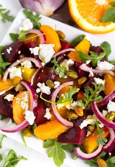 a salad with beets, oranges and feta cheese on top is shown