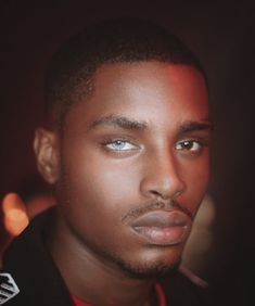 a close up of a person wearing a black jacket and red shirt with blue eyes