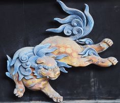 a statue of a lion on the side of a building with its tail curled up