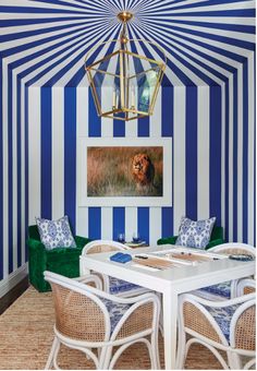 a dining room with blue and white striped walls, wicker chairs and a large painting on the wall