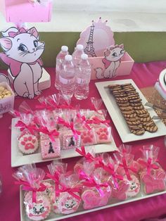 a table topped with lots of desserts and treats on top of a pink table cloth