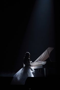 a woman sitting at a piano in the dark