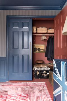 a blue door is open in a room with red walls and rugs on the floor