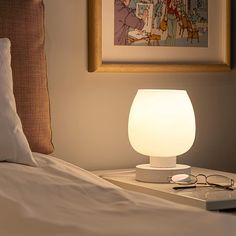 a white lamp sitting on top of a bed next to a pillow