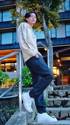 a young man standing on steps in front of a building with stairs leading up to it