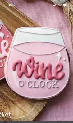 a cookie with the words wine o'clock on it next to a wooden board