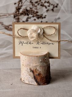 a place card holder made from a tree stump with a ribbon tied around the top