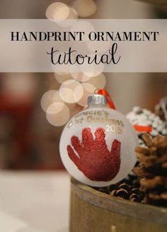 a handprint ornament sitting on top of a wooden container filled with pine cones