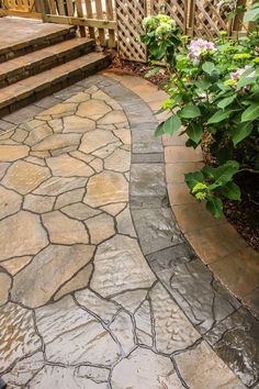 a stone walkway with steps and flowers in the background