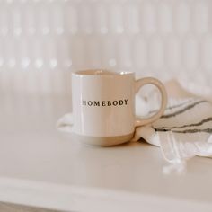 a white coffee mug sitting on top of a counter next to a towel and some glasses