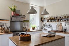 a kitchen with wooden counter tops and hanging lights over the stove top, along with pots and pans