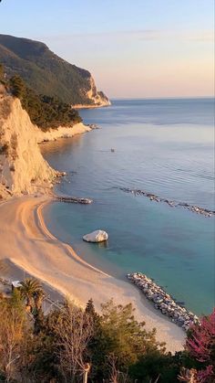 a sandy beach next to the ocean with boats on it