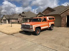 an orange and white truck parked in front of a house