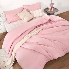 a bed with pink sheets and pillows on it