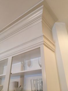 the shelves in this kitchen have wine glasses on them, and empty cups are sitting on top