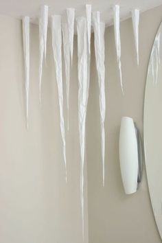 icicles hang from the ceiling in front of a mirror and light fixture with a wall mounted hair dryer next to it