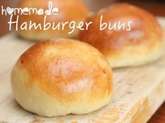 two bread buns sitting on top of a cutting board with the words homemade hamburger buns