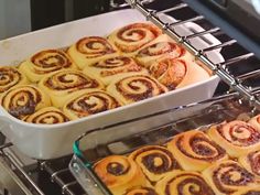 two pans filled with cinnamon rolls sitting on top of an oven