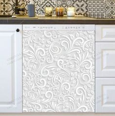 a kitchen with white cabinets and an ornate design on the wall behind it is a counter top