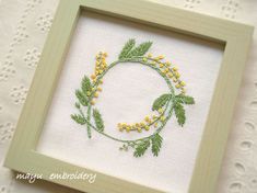 an embroidered frame with yellow flowers and green leaves on the edge, sitting on a white lace tablecloth