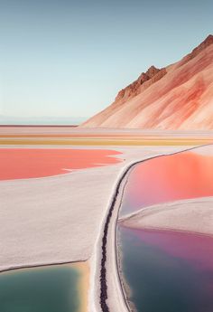 the water is pink and green in this desert landscape, with mountains in the background