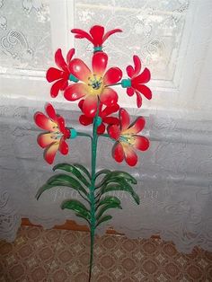 a vase with red flowers in front of a window