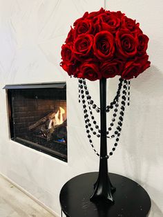 a vase filled with red roses sitting on top of a table next to a fireplace