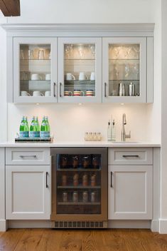 a kitchen with white cabinets and glass doors on the cupboards are filled with dishes