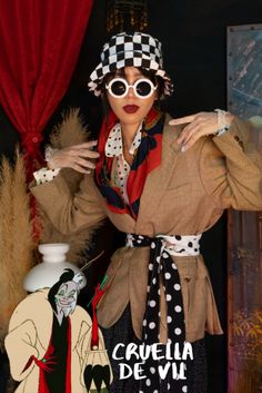 a woman wearing sunglasses and a hat standing in front of a red curtain with her hands on her hips