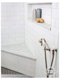 a white tiled shower with two hand held shower heads