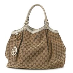 This is an authentic GUCCI Monogram Large Sukey Tote in Off White. This chic tote is crafted of classic brown on beige Gucci GG monogram canvas with an off white leather trim. The bag features rolled leather shoulder straps with light brass links and a top crest of leather with a hanging light brass Gucci interlocking GG logo charm. The top is open to a spacious brown fabric interior with a zipper pocket. Gg Monogram, Gucci Monogram, Gg Logo, Classic Brown, Brown Fabric, Hanging Light, Monogram Canvas, Leather Trim, White Leather