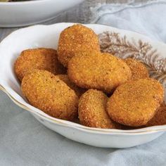 a white bowl filled with fried food on top of a table next to a cloth