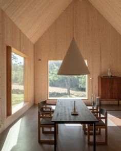 a dining room with wooden walls and flooring has a large table in the center