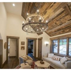 a living room filled with lots of furniture and a chandelier hanging from the ceiling