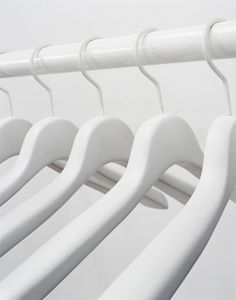 white clothes hangers are lined up against the wall