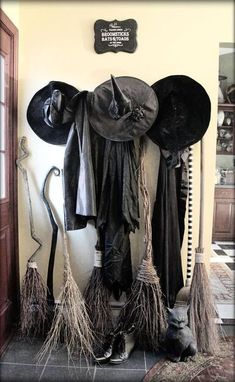 an assortment of hats and brooms are displayed on the wall in front of a door