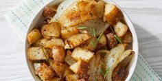 a white bowl filled with cooked potatoes on top of a blue and white napkin next to a fork