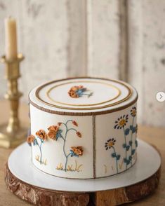 a decorated cake sitting on top of a wooden table next to a candle and some flowers