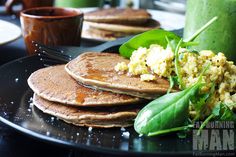 pancakes with eggs and spinach on a plate next to a green smoothie cup