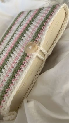 a crocheted purse sitting on top of a white bed next to a pillow