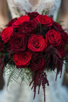 a bride holding a bouquet of red roses