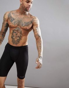 a man with tattoos on his body and no shirt standing in front of a gray background