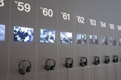 headphones are lined up on the wall in front of numbers and pictures with headsets hanging from them