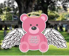 a pink teddy bear with an angel halo on it's head sitting in the grass