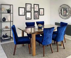 a dinning room table with blue chairs and pictures on the wall above it,