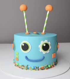 a blue cake with two green and orange candles in the shape of a monster's face