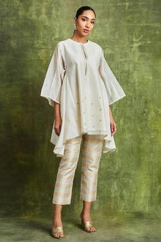 Off-white handwoven chanderi top with zari embroidery. Comes with banarasi brocade pant and an inner.
Components: 3
Pattern: Embroidered
Type Of Work: Zari
Neckline: Round
Sleeve Type: Flared Sleeves
Fabric: Top : Handwoven chanderi, Pant : Banarasi brocade
Color: Off White
Other Details: 
Asymmetric-cut hemline on top
Occasion: Work - Aza Fashions Kaftan Pattern, White Kaftan, Drape Pants, Dress Design Patterns, Top And Pants Set, Trendy Fashion Outfits, Modest Fashion Outfits, Long Shirt, Embroidered Top