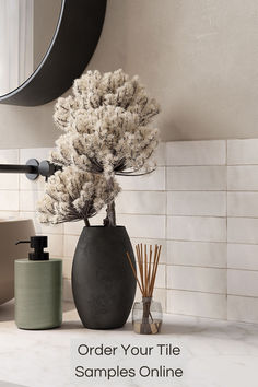 a vase with flowers in it sitting on a counter next to a soap dispenser