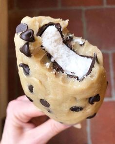 a person holding up a cookie doughnut with chocolate chips and marshmallows