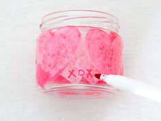 a jar filled with pink hearts next to a marker